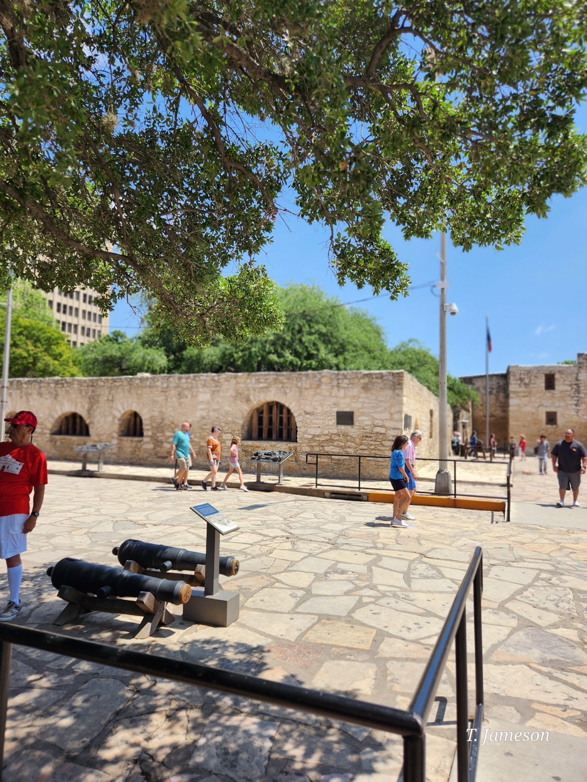 Stone fortification and shaded courtyard with visitors in bright afternoon light.